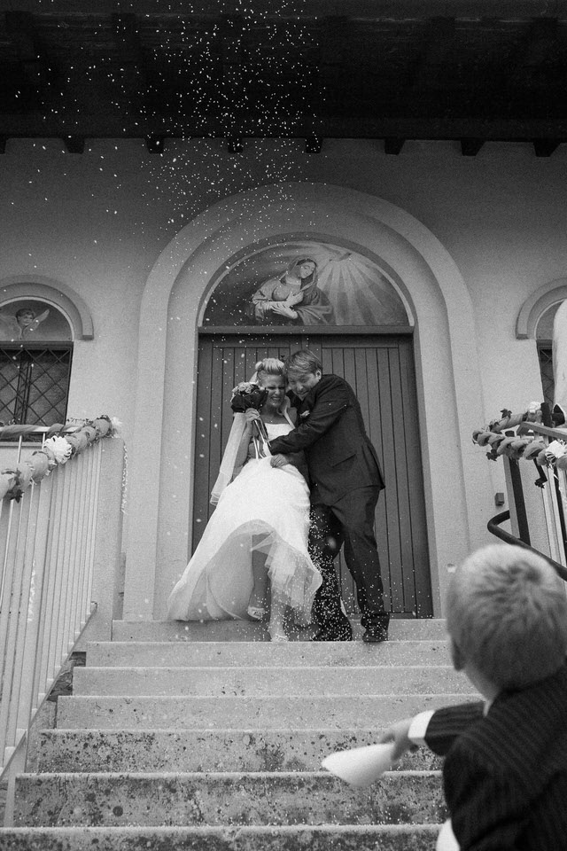 Black and white photo of newly wedded couple showered with confetti