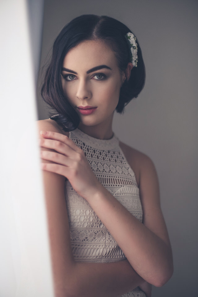 A photo of a woman in a white dress looking at the camera