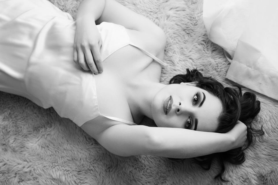 A black and white photo of a woman lying down looking at the camera