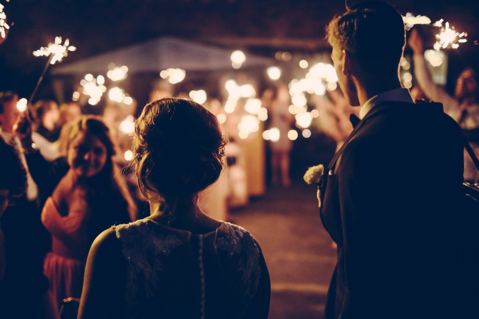 An evening wedding shot with bokeh lights and people